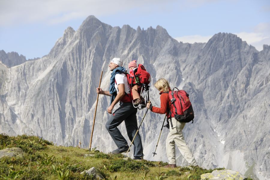 Pärchen wandert mit dem Baby im Rücksack in der Höhenluft am Arlberg